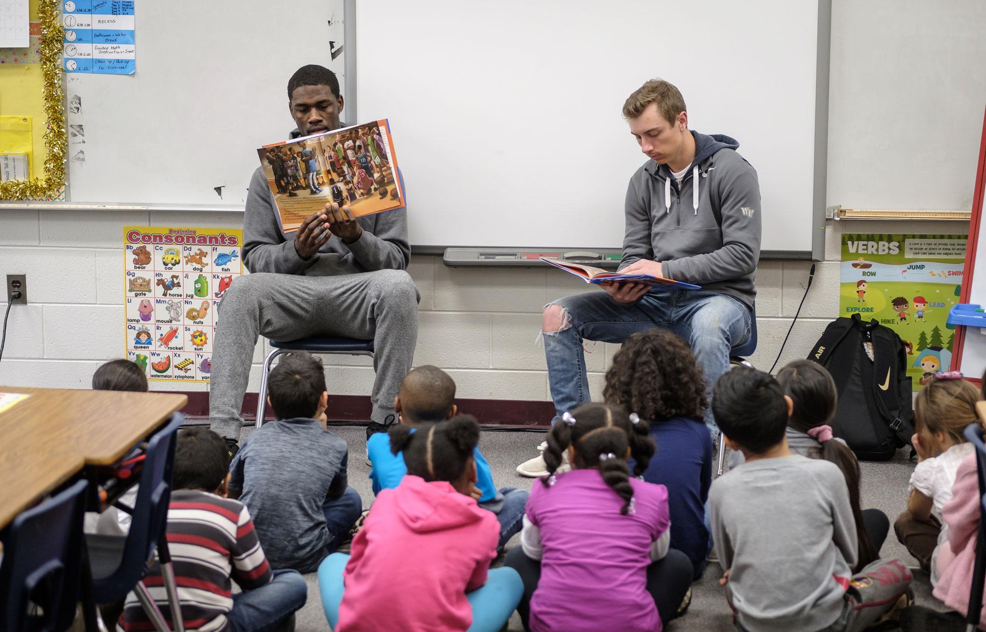 Two teachers reading to a group of young students